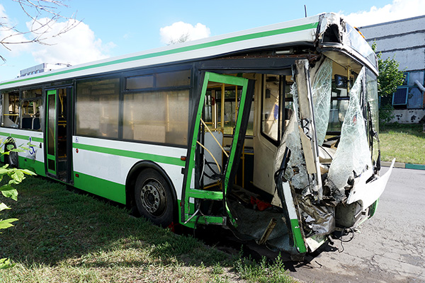 A green bus with a crushed door from a bus accident