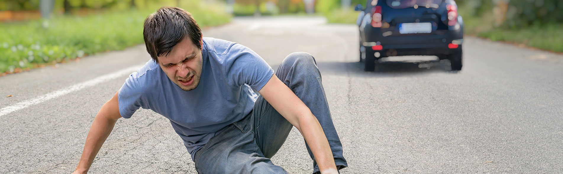 a man lying on the road with a car driving away following a hit and run