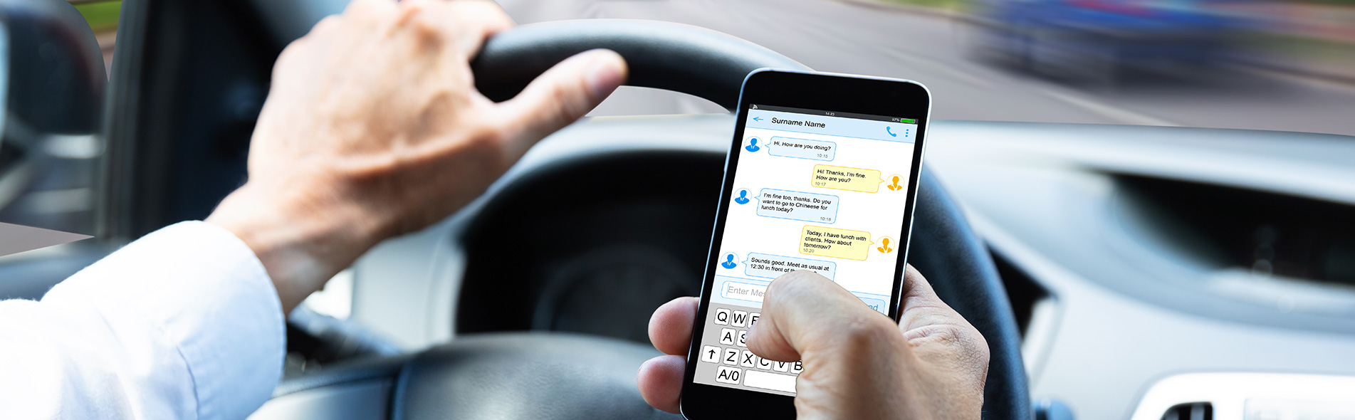 Man typing on a mobile phone while driving