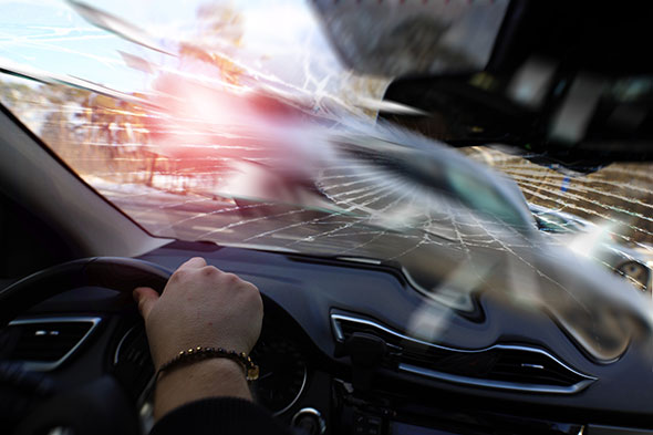 A head-on collision showing the inside of a car with a cracked windshiel