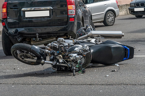 A motorcycle accident with a motorcycle lying on the road with a car in the background