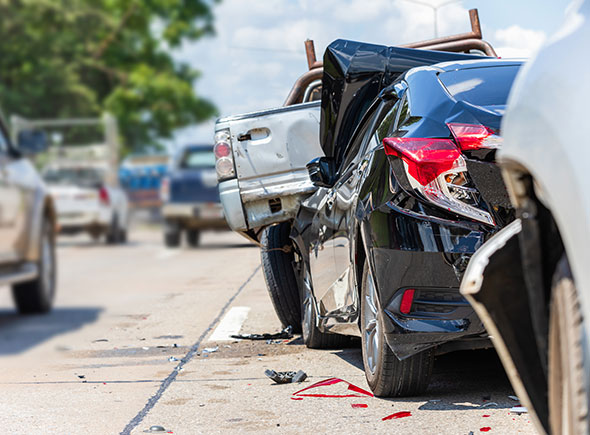 A multiple vehicle accident with a black car wrecked between two other vehicles