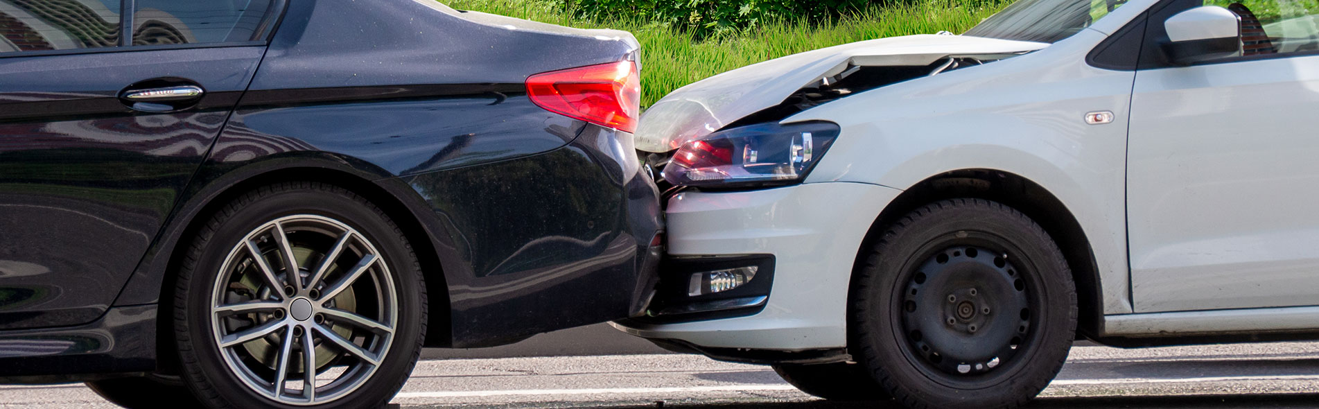 A multiple vehicle accident with two passenger cars crashed bumper-to-bumper on the side of a road