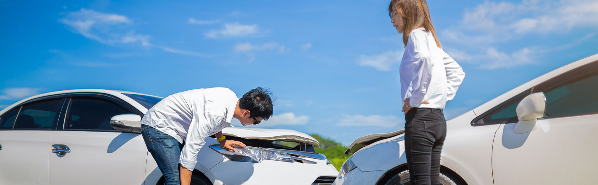 a man who is an uninsured motorist inspects a white car for damage after an accident