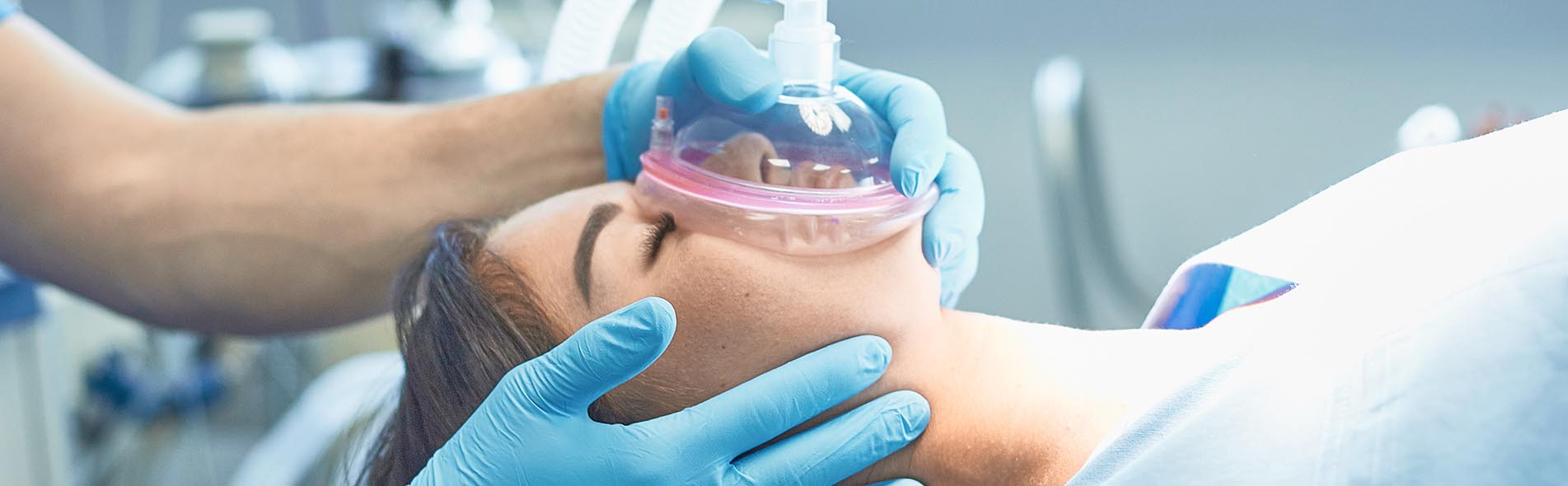 A woman lying on an operating table receiving anesthesia