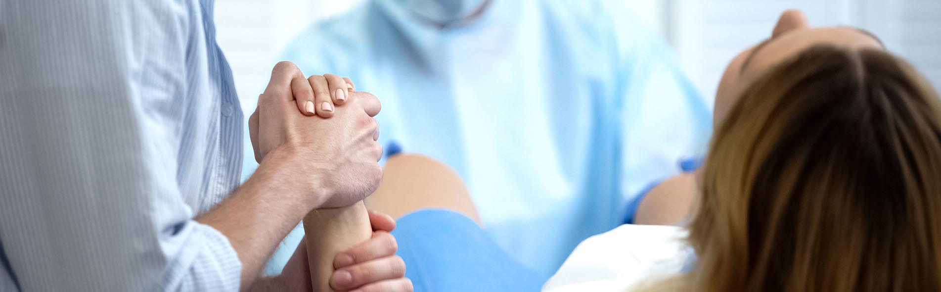 A husband holds his wife’s hand as she gives birth