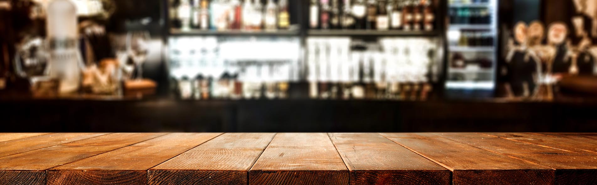 A wide shot of a bar with shelves full of liquor in the background