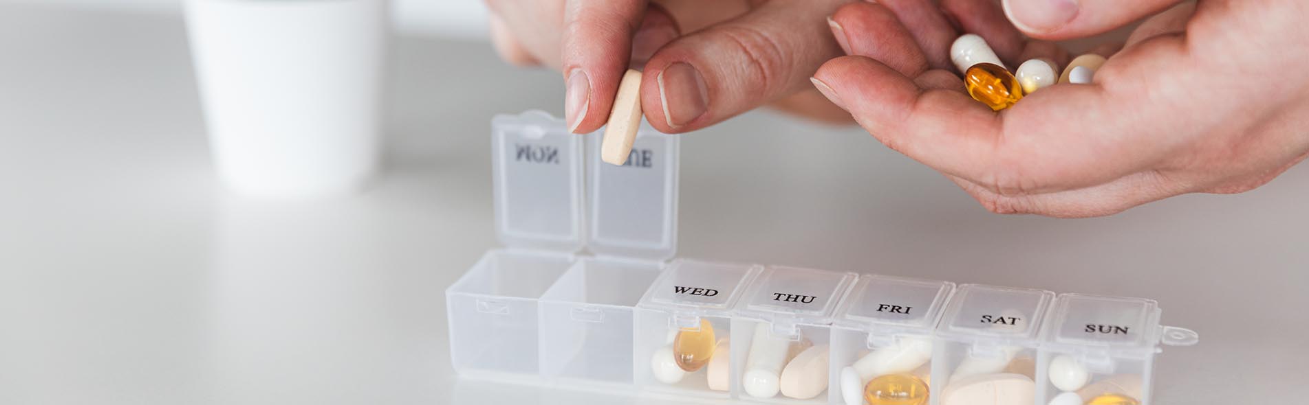 A human hand places pills into a pill sorter