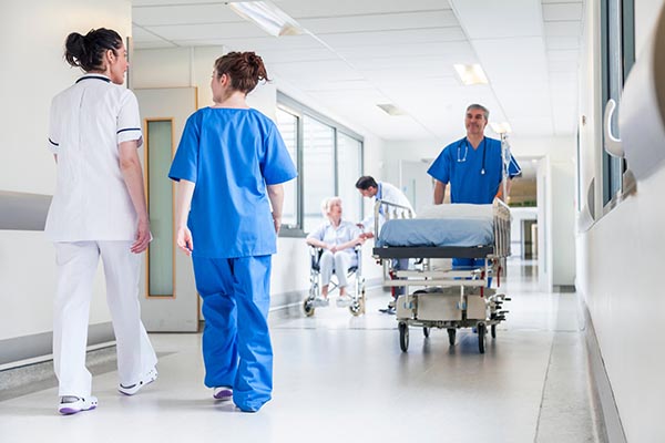 Male nurse pushing stretcher gurney bed in hospital corridor wit