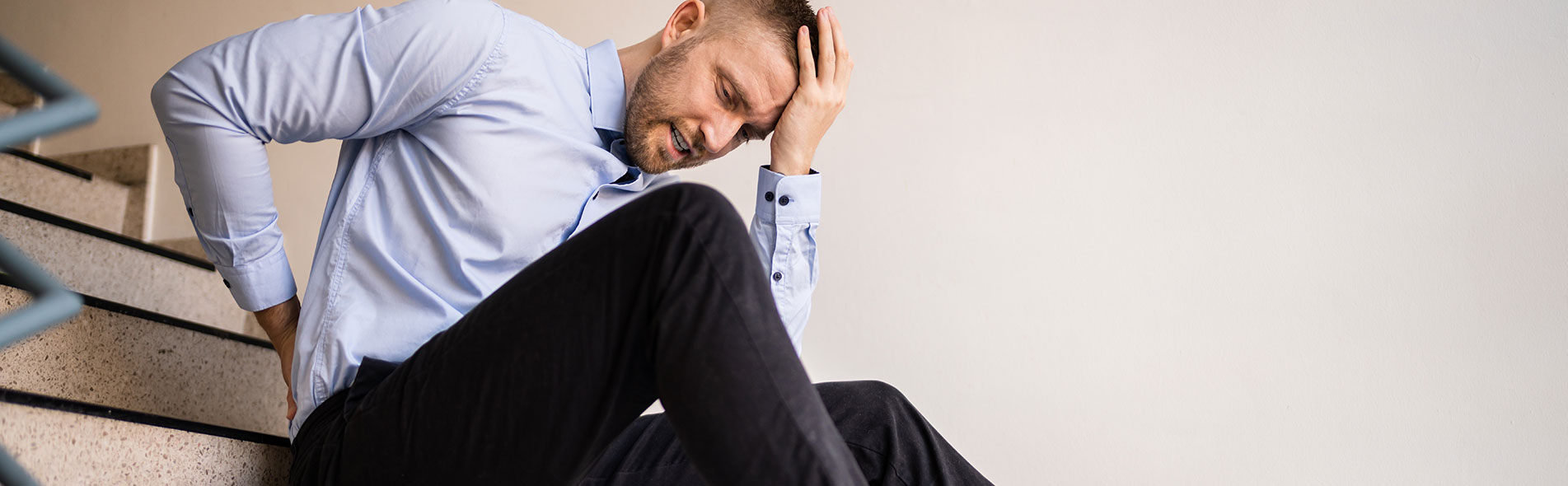 A man holds his head with one hand and his back with another after falling down the stairs in a premises liability case