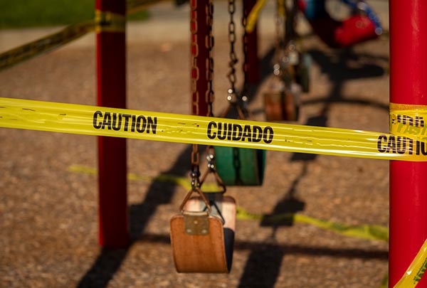 Empty saddle style swings at a playground covered in yellow caut