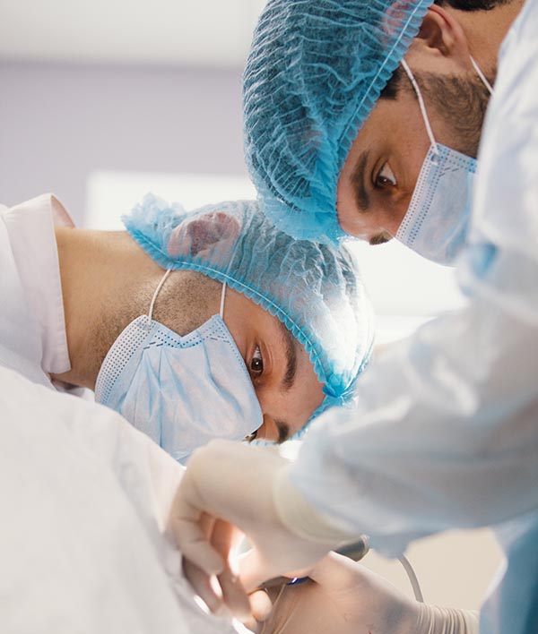 Two surgeons in blue robes make operation in surgery room