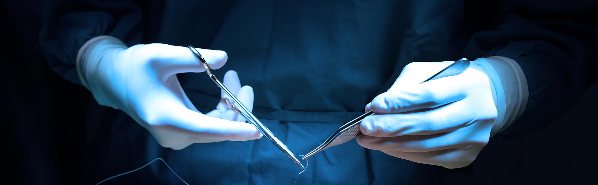 A surgeon holds tools as they prepare to operate on a patient